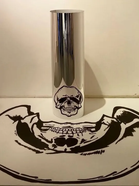 Anamorphic drawing: a stretched skull on paper reflects as an upright skull in a mirrored cylinder